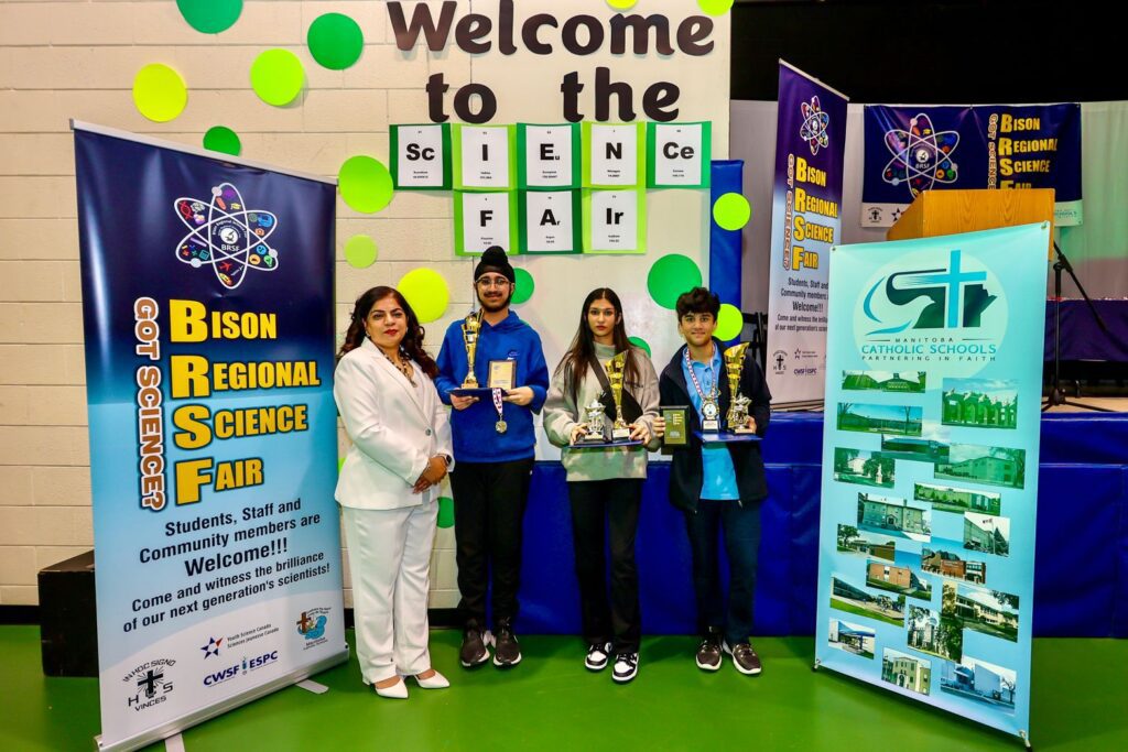 Le Dr Anju Bajaj à trois étudiants se tient devant le panneau Bienvenue à l'Expo-sciences.