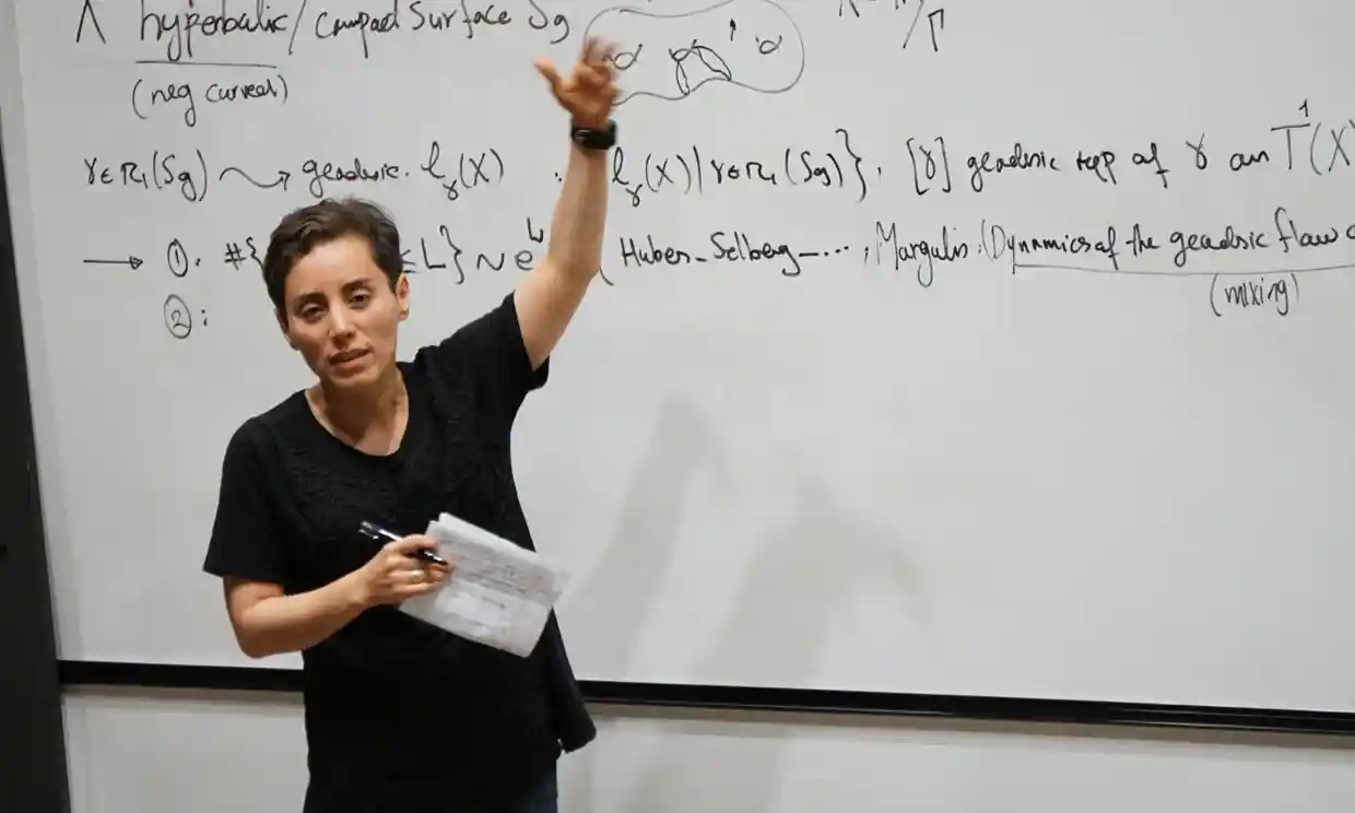 Maryam Mirzakhani spiega un problema di matematica davanti a una lavagna bianca
